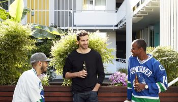 The Burrard Hotel: Three men in hockey jerseys drinking beer. Gay-friendly hotel in Vancouver with colorful doors and a social atmosphere.