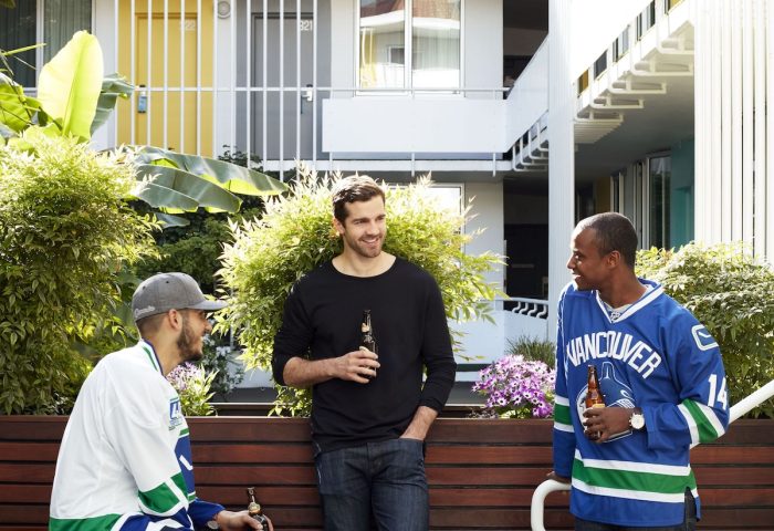 The Burrard Hotel: Three men in hockey jerseys drinking beer. Gay-friendly hotel in Vancouver with colorful doors and a social atmosphere.