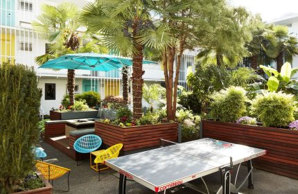The Burrard Hotel's gay-friendly courtyard. Palm trees, colorful chairs, and a ping pong table create a fun, vibrant outdoor space.