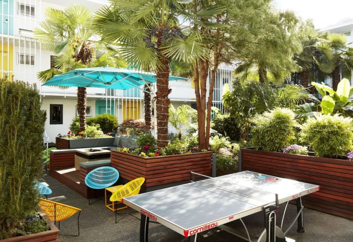 The Burrard Hotel's gay-friendly courtyard. Palm trees, colorful chairs, and a ping pong table create a fun, vibrant outdoor space.