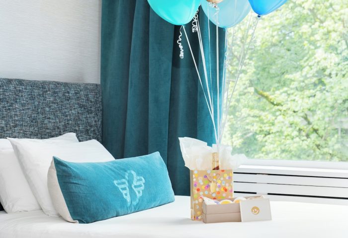 Gay-Friendly Hotel The Burrard Hotel room with balloons, gifts on a bed. A welcoming scene for LGBTQ+ travelers. Vancouver hotel.