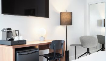 The Burrard Hotel room detail. Gay-friendly hotel with desk, chair, mini fridge, coffee maker, and lamps. Modern design for gay men travel.