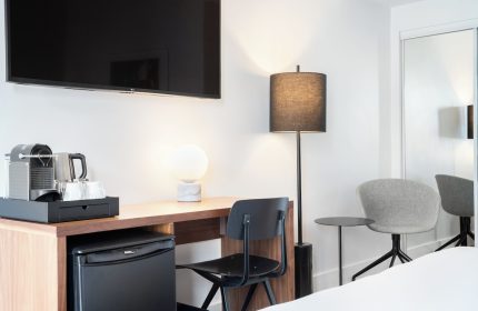 The Burrard Hotel room detail. Gay-friendly hotel with desk, chair, mini fridge, coffee maker, and lamps. Modern design for gay men travel.
