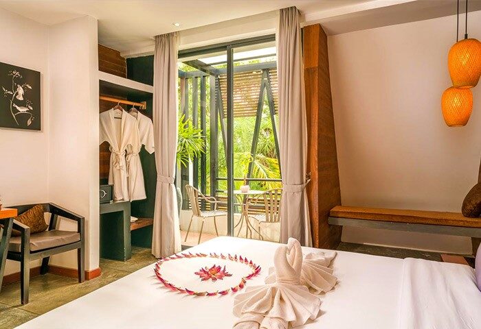 Gay-Friendly Hotel The Butterfly Pea room. Balcony view, swan towels, and flower petals on bed. A welcoming space for gay travelers.