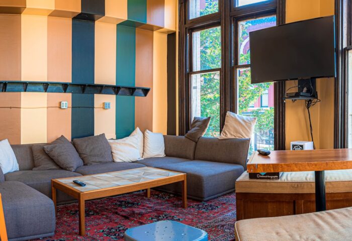 Cambie Hostel Gastown's gay-friendly hotel lounge. Cozy seating area with a large sofa, TV, and colorful striped walls. Great for gay travelers.