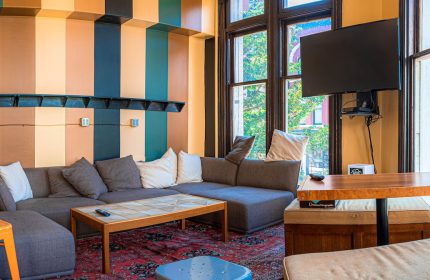 Cambie Hostel Gastown's gay-friendly hotel lounge. Cozy seating area with a large sofa, TV, and colorful striped walls. Great for gay travelers.
