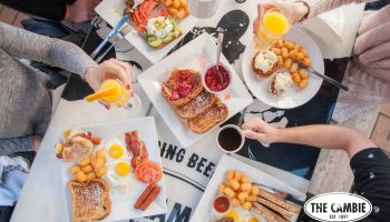 Brunch at The Cambie Hostel Gastown. Plates with eggs, bacon, toast, and coffee. Gay-friendly hotel with delicious food options.