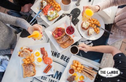 Brunch at The Cambie Hostel Gastown. Plates with eggs, bacon, toast, and coffee. Gay-friendly hotel with delicious food options.