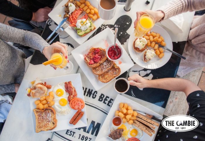 Brunch at The Cambie Hostel Gastown. Plates with eggs, bacon, toast, and coffee. Gay-friendly hotel with delicious food options.