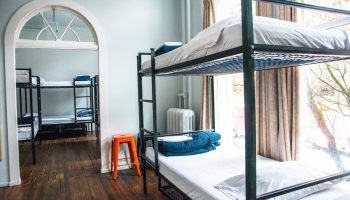 Dorm room at The Cambie Hostel Gastown. Bunk beds, hardwood floors, and an orange stool. Gay-friendly hotel for budget travelers.