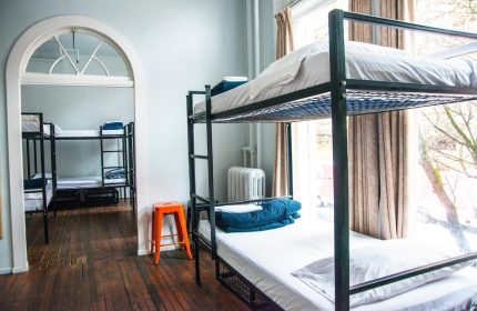 Dorm room at The Cambie Hostel Gastown. Bunk beds, hardwood floors, and an orange stool. Gay-friendly hotel for budget travelers.