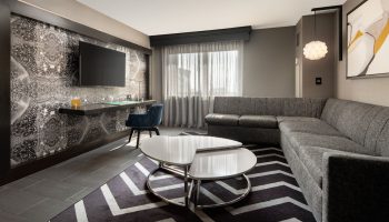 The Clancy Autograph Collection gay-friendly hotel room. Modern design with a desk, TV, sectional sofa, and stylish decor. A comfortable stay.