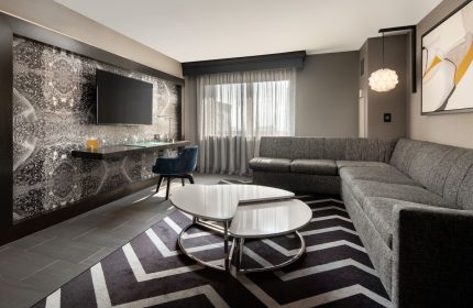 The Clancy Autograph Collection gay-friendly hotel room. Modern design with a desk, TV, sectional sofa, and stylish decor. A comfortable stay.