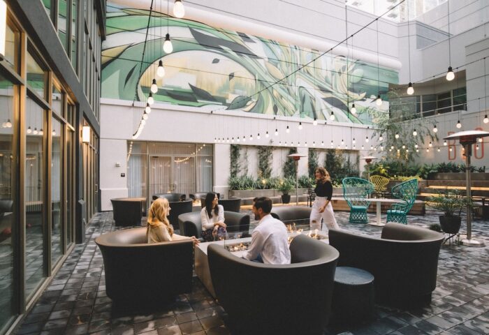 The Clancy Autograph Collection gay-friendly hotel's outdoor courtyard. People gather around a fire pit. String lights add ambiance.