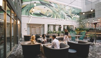 The Clancy Autograph Collection gay-friendly hotel's outdoor courtyard. People gather around a fire pit. String lights add ambiance.