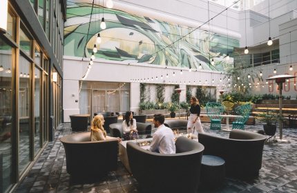 The Clancy Autograph Collection gay-friendly hotel's outdoor courtyard. People gather around a fire pit. String lights add ambiance.