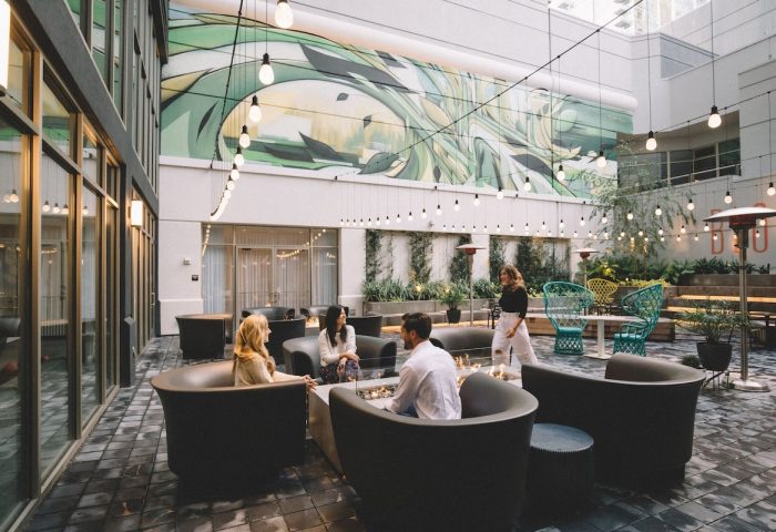 The Clancy Autograph Collection gay-friendly hotel's outdoor courtyard. People gather around a fire pit. String lights add ambiance.