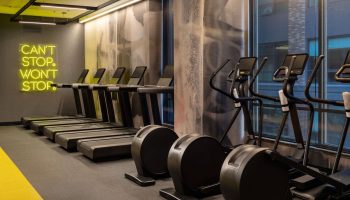 Gym at The Clancy Autograph Collection, a gay-friendly hotel. Treadmills and ellipticals are available for guests' use. Can't stop, won't stop neon.