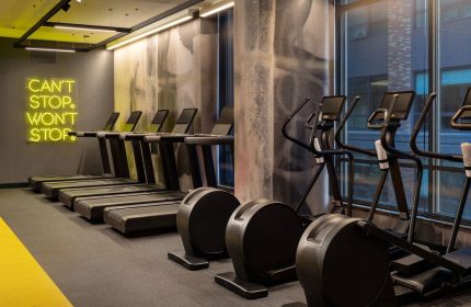 Gym at The Clancy Autograph Collection, a gay-friendly hotel. Treadmills and ellipticals are available for guests' use. Can't stop, won't stop neon.
