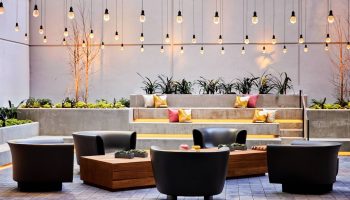 The Clancy Autograph Collection gay-friendly hotel outdoor lounge area with string lights, chairs, and tiered seating. Great for gay travelers.