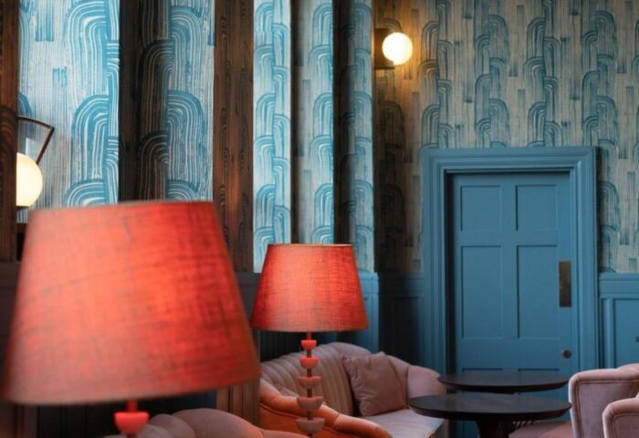 The Clarence, a gay-friendly hotel: Lounge area with pink chairs, tables, lamps, and blue patterned wallpaper. Gay travel advice.