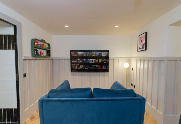 Cozy lounge area at The Clarence, a gay-friendly hotel. Features a blue sofa, TV, snacks, and stylish decor for gay men's travel comfort.