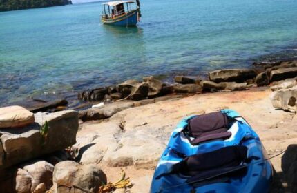 The Cobble Beach Hotel: Kayak on the shore near a gay-friendly hotel. Boat on turquoise water. Ideal for gay travel, relaxation, and adventure.