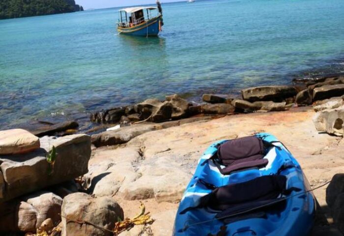 The Cobble Beach Hotel: Kayak on the shore near a gay-friendly hotel. Boat on turquoise water. Ideal for gay travel, relaxation, and adventure.