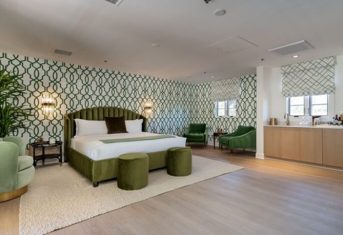 Gay-Friendly Hotel: The Colony Palms Hotel room featuring a king bed, green accents, patterned wallpaper, & modern design. Perfect for gay travel.