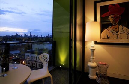 Balcony view at The Cullen, Melbourne's gay-friendly Art Series hotel. Wine, city skyline, & unique art create a welcoming atmosphere for travelers.