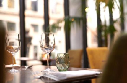 Fine dining at The Dilly, a gay-friendly hotel. Wine glasses and elegant table setting. Upscale travel experience for gay men.