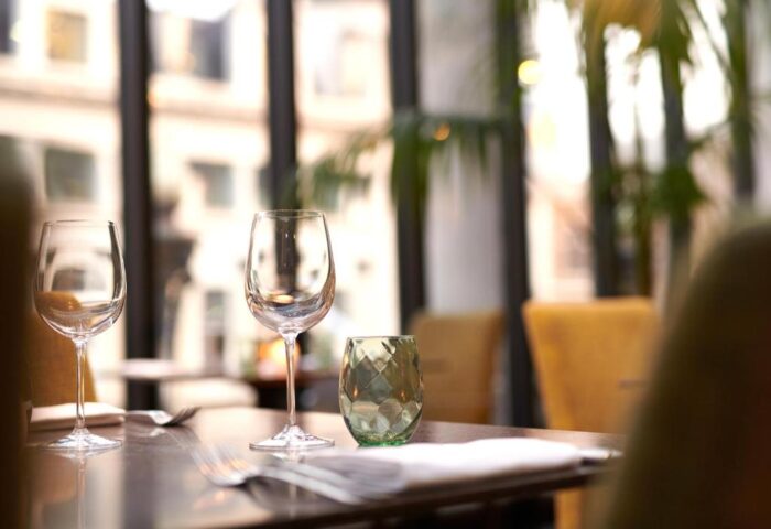 Fine dining at The Dilly, a gay-friendly hotel. Wine glasses and elegant table setting. Upscale travel experience for gay men.