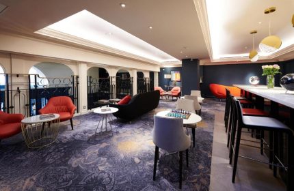 The Dilly, a gay-friendly hotel: Chic lounge area with bar seating, chess table, and stylish decor. A modern, welcoming space.