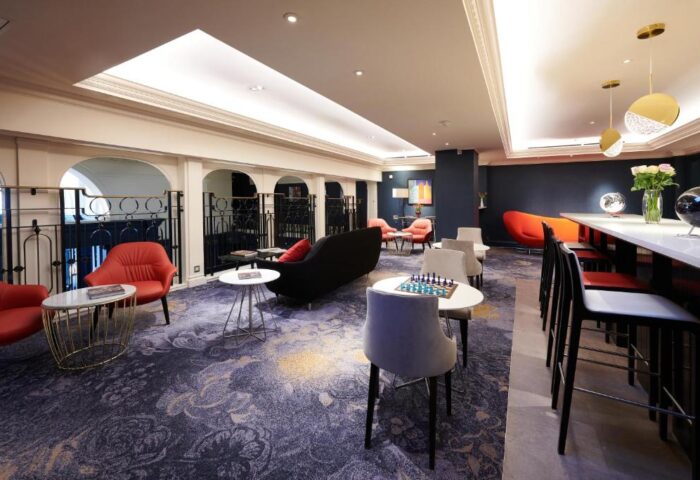 The Dilly, a gay-friendly hotel: Chic lounge area with bar seating, chess table, and stylish decor. A modern, welcoming space.