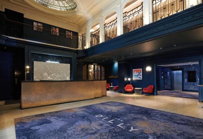 The Dilly, a gay-friendly hotel: grand lobby with a reception desk, seating area, and ornate architectural details. Upscale travel for gay men.