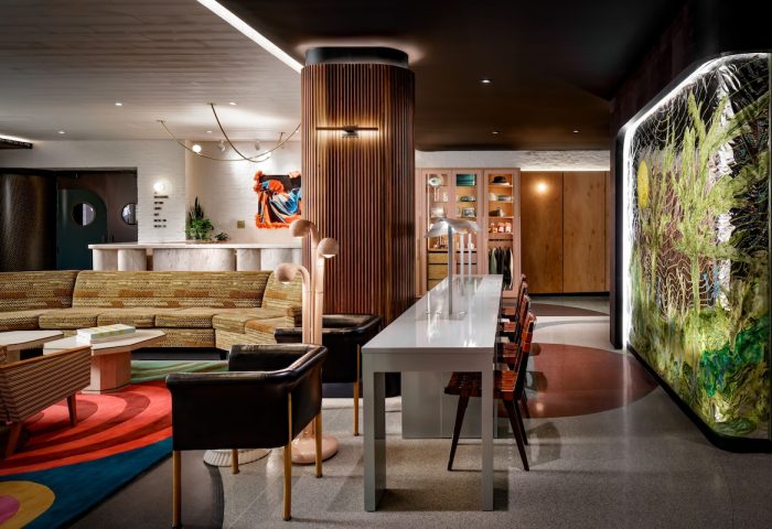 The Drake Hotel's gay-friendly interior features a stylish lobby with a retro sofa, long table, and colorful artwork. A welcoming space for travelers.