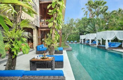 The Elysian Boutique Villa Hotel's pool. Gay-friendly hotel with poolside cabanas, blue cushions, and lush greenery. A tropical gay travel paradise.