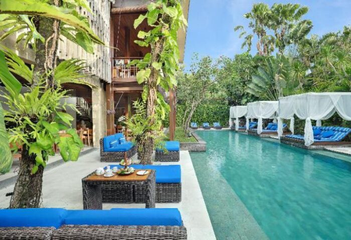 The Elysian Boutique Villa Hotel's pool. Gay-friendly hotel with poolside cabanas, blue cushions, and lush greenery. A tropical gay travel paradise.