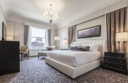 Fairmont San Francisco Hotel room. Gay-friendly hotel with a luxurious king bed, chandelier, and city views. Perfect for gay travelers.