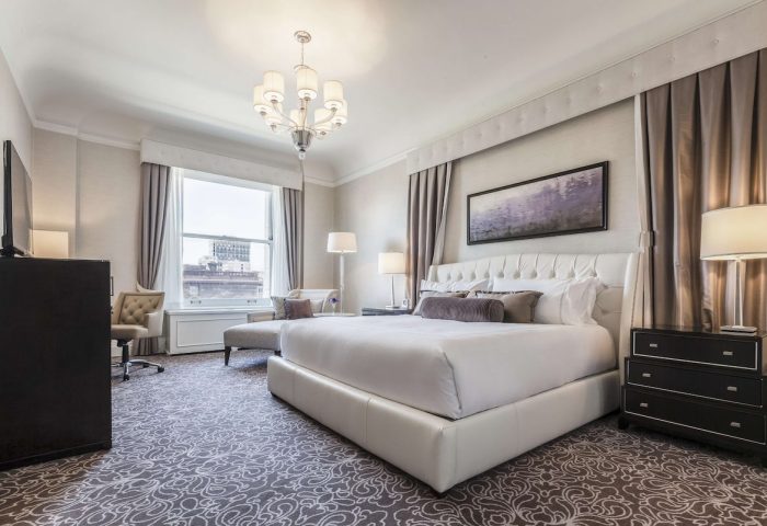 Fairmont San Francisco Hotel room. Gay-friendly hotel with a luxurious king bed, chandelier, and city views. Perfect for gay travelers.