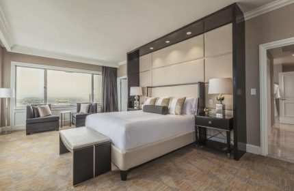 Fairmont San Francisco Hotel room. Luxurious gay-friendly hotel bedroom with a king-size bed, seating area, and city view. Upscale travel.