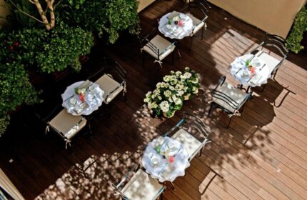 The Fifteen Keys Hotel's pet-friendly patio. Tables with white tablecloths, chairs, and flowers on a wooden deck. Gay-friendly hotel.