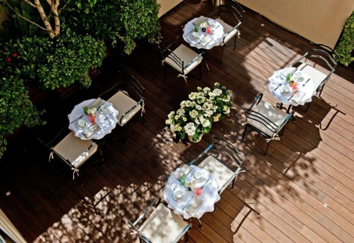 The Fifteen Keys Hotel's pet-friendly patio. Tables with white tablecloths, chairs, and flowers on a wooden deck. Gay-friendly hotel.