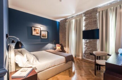 Bedroom at The Fifteen Keys Hotel, a gay-friendly and pet-friendly hotel. Features a bed, TV, brick wall, and stylish décor.