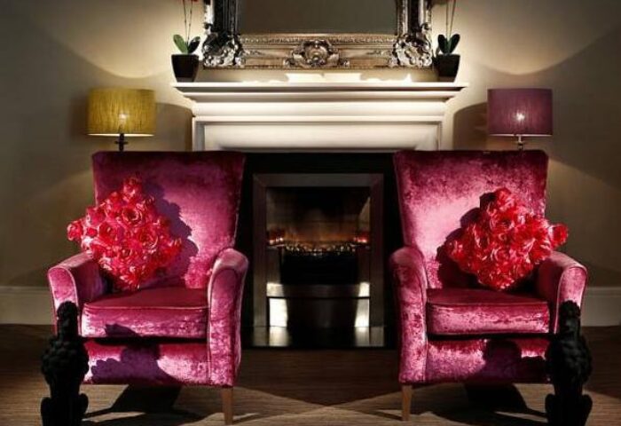 Gay-Friendly Hotel The Fleet: Two plum velvet chairs with rose pillows face a fireplace. Lamps and poodle statues add to the ambiance.