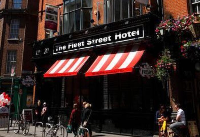 The Fleet Street Hotel, a gay-friendly hotel. Red and white awnings over the entrance. People walk and sit outside this Dublin hotel.