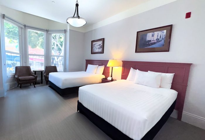 The Grove Inn: Gay-friendly hotel room with two beds, sitting area, and natural light. A comfortable stay for gay travelers.