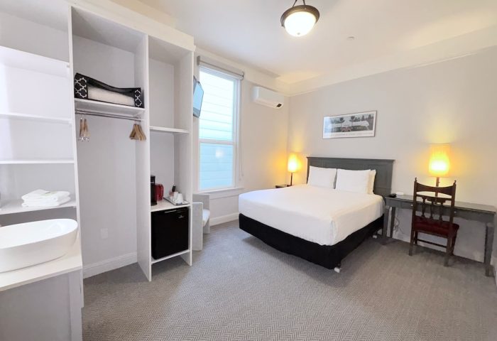 Grove Inn gay-friendly hotel room. Queen bed, desk, chair, wardrobe, sink, mini-fridge, and TV. Modern, clean design for gay travelers.