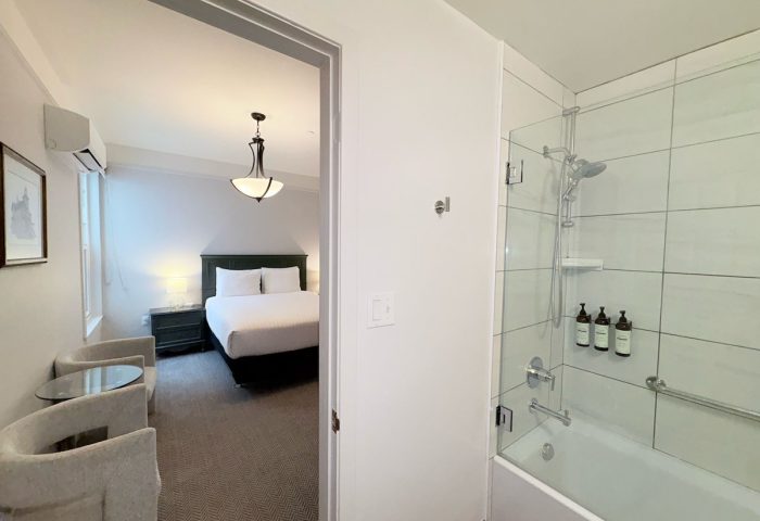 The Grove Inn, gay-friendly hotel room. View of bed, chairs, and bathroom with tub and shower. Modern, clean design for gay men travelers.