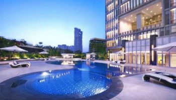 The Grove Suites by GRAND ASTON pool. Gay-friendly hotel with outdoor pool, lounge chairs, and city view. Luxury travel for gay men.
